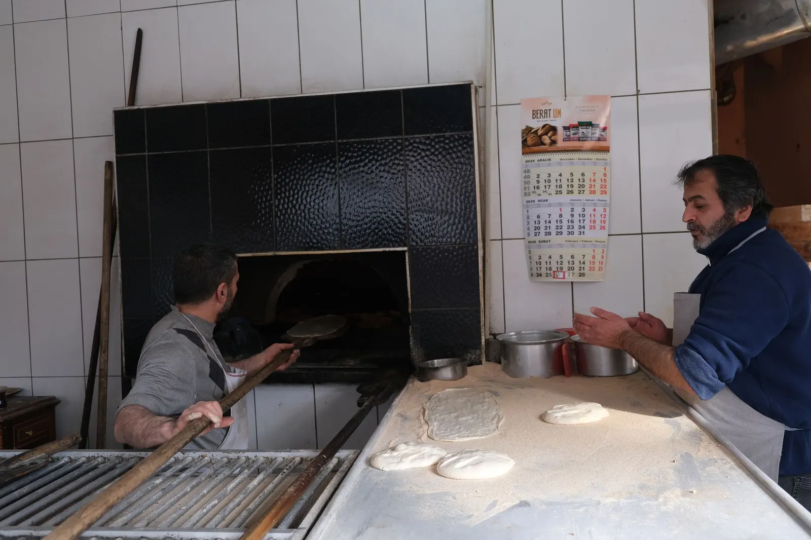 Boulangers faconnant la pate devant le four a bois du fournil